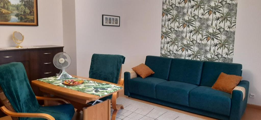 a living room with a blue couch and a table at Mieszkanie w Giżycku in Giżycko