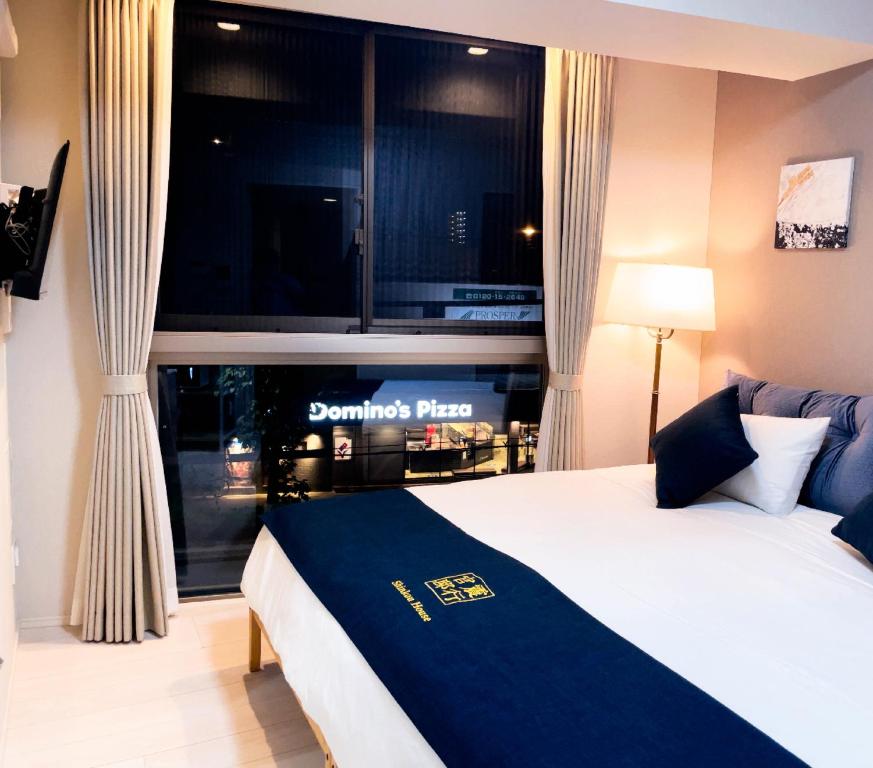 大阪市にあるShinkou House UEのベッドと大きな窓が備わるホテルルームです。