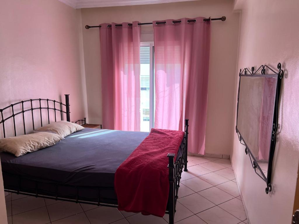 a bedroom with a bed and a window with pink curtains at Appartement Marhaba in Agadir