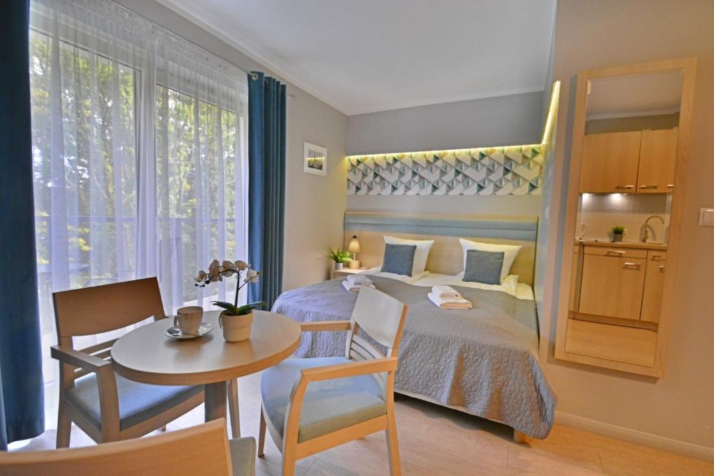 1 dormitorio con cama, mesa y comedor en Apartamenty Cesarskie - Apartamenty Bryza - Parking, en Świnoujście