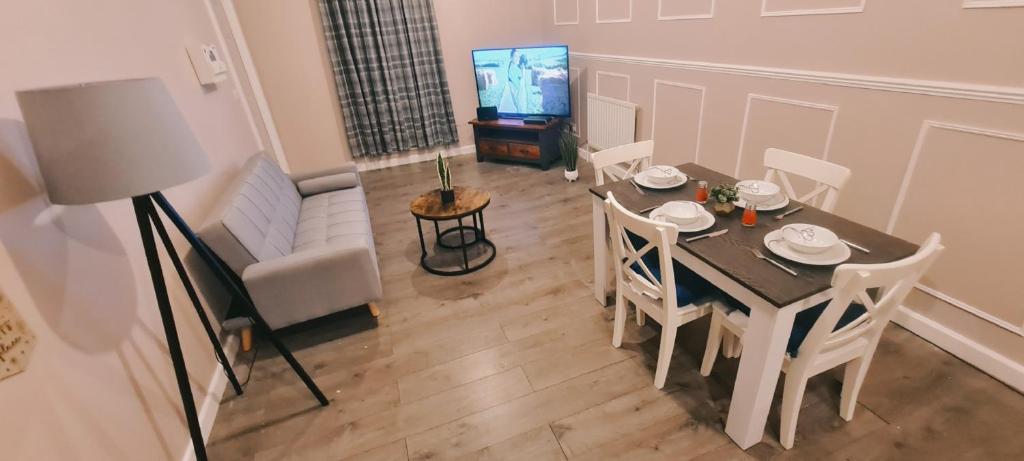 ein Wohnzimmer mit einem Tisch, Stühlen und einem TV in der Unterkunft Charming 1-Bed Apartment in Barnsley in Barnsley