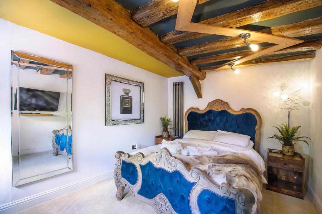 a bedroom with a blue bed and a mirror at King Suite In 600 Year Old Manor House In Saffron Walden North Essex in Saffron Walden