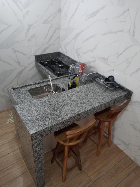 a kitchen counter with a sink and two chairs at Flat 02 com Varanda - Avenida Hospedagem in São Thomé das Letras