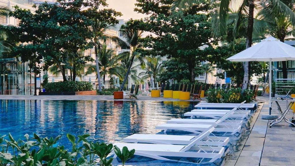 - une piscine avec des chaises longues blanches et un parasol dans l'établissement Kaira Boutique Hotel, à Duong Dong