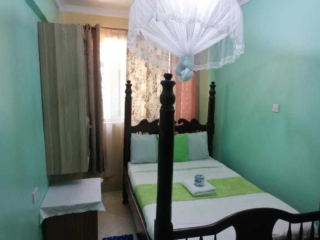 een kleine slaapkamer met een hemelbed bij Milimani Greens Inn in Kakamega