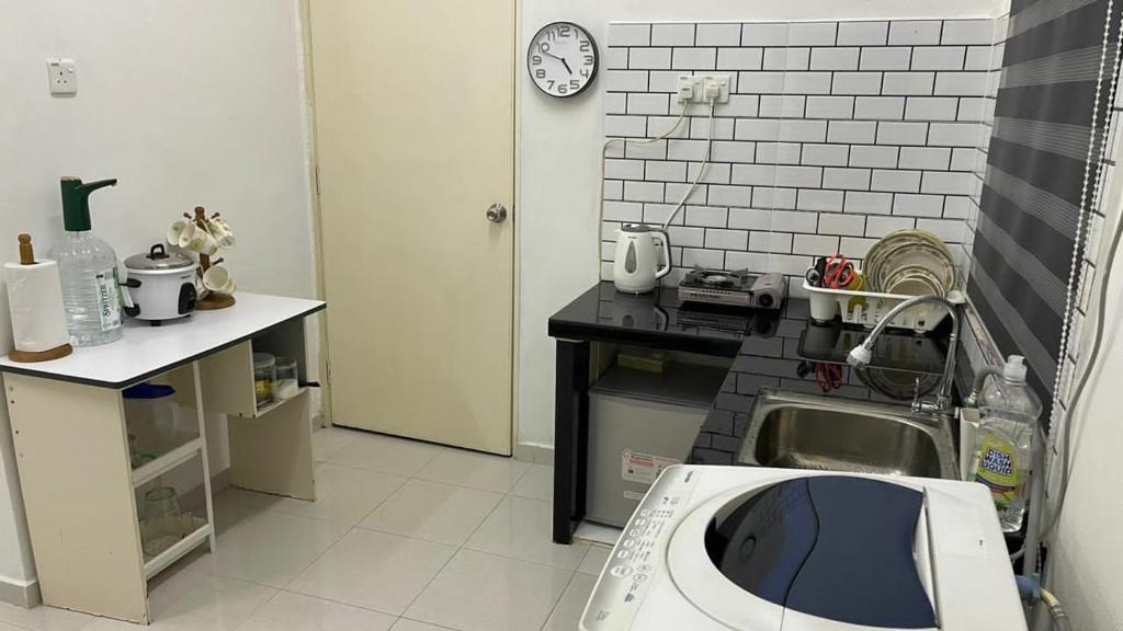 a kitchen with a sink and a clock on the wall at Rumah Kami Homestay in Butterworth