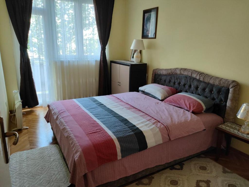 sypialnia z łóżkiem z kolorowym kocem i oknem w obiekcie Apartman Sunce w mieście Podgorica