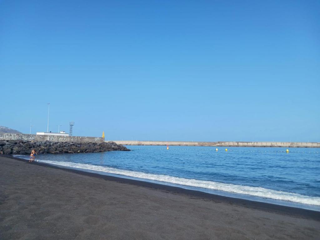 una spiaggia con acqua blu e un molo roccioso di Mar y reina a Puerto del Rosario
