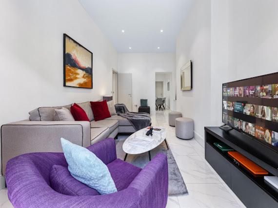 a living room with a purple couch and a tv at Harley Street Luxury Snug in London
