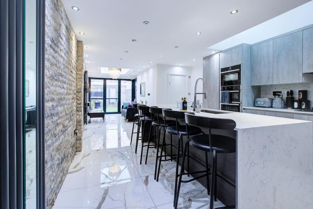 a kitchen with a bar with black stools at Luxurious House Leyton sleep7+garden next to Stratford in London