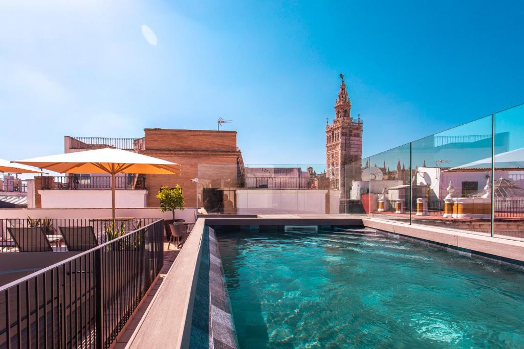 una piscina en la parte superior de un edificio con una torre del reloj en Casa Alhaja by Shiadu, en Sevilla