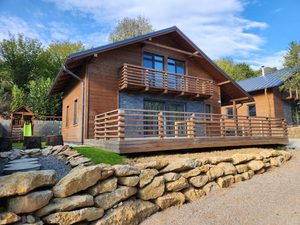 a log cabin with a rock wall in front of it at Chalet Fiona with jacuzzi in Mýto pod Ďumbierom