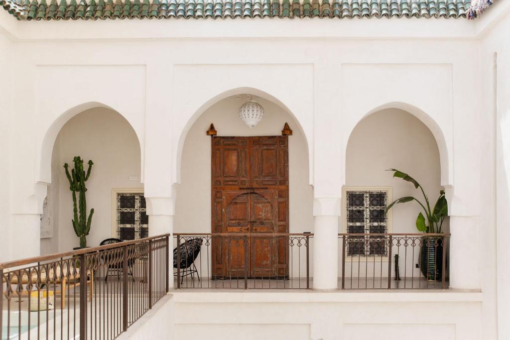 une grande porte en bois dans un bâtiment blanc avec des arches dans l'établissement Riad La Lumière d'Étoile, à Marrakech