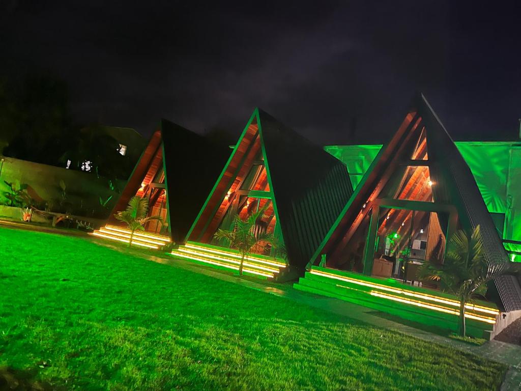 a house lit up at night with green lights at Hotel e Cabanas Perau CABANAS in Ametista do Sul