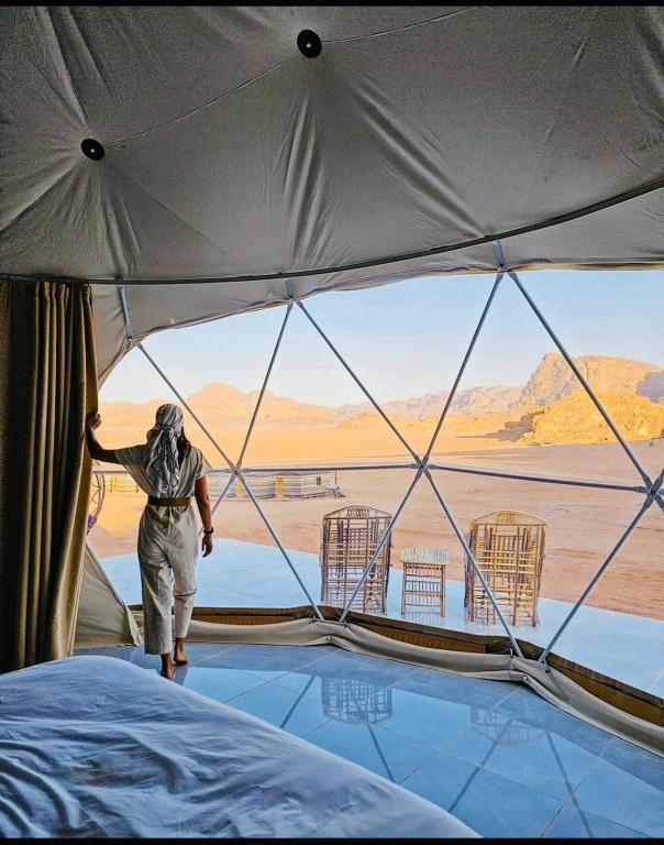 ワディ・ラムにあるRum Goldeneye luxury campの砂漠を見下ろすテント内に立つ者