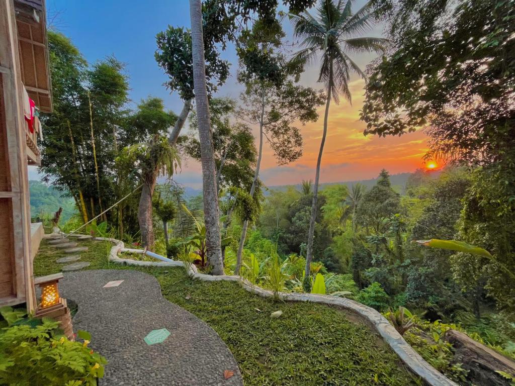 un camino que conduce a una casa con una puesta de sol en el fondo en Kalamanthana Bali - Nature with Modern Comfort, en Selat