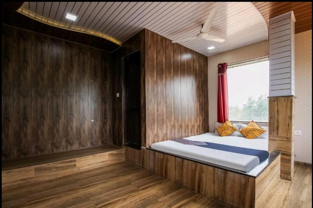 uma cama num quarto de madeira com uma janela em New natraj em Chikalda