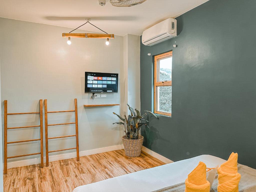 a bedroom with a bed and a flat screen tv at Outpost Hostel - Coron in Coron