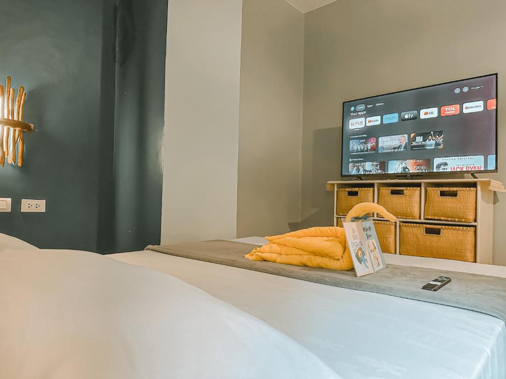 a bedroom with a bed with a tv on the wall at Outpost Hostel - Coron in Coron