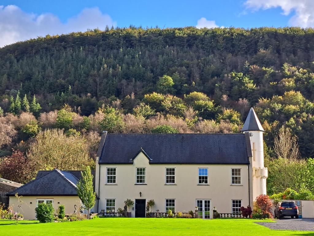 a large white house with a hill in the background at Glangwili Mansion - Luxury 5 star Bed & Breakfast in Carmarthen