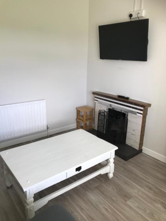 Habitación con cama blanca y TV en la pared. en Brigid M’s Farm House, en Killashandra