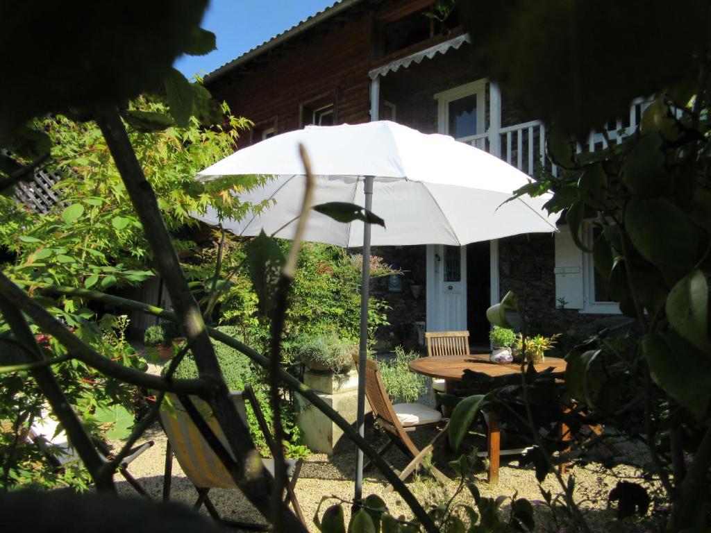 Le Balcon Commingeois في Chein-Dessus: وجود مظلة بيضاء تجلس أمام طاولة