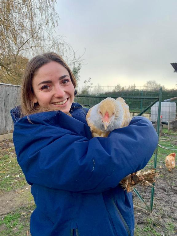 une femme tenant un poulet dans les bras dans l'établissement Nuit au calme, en pleine nature, à Bagneux