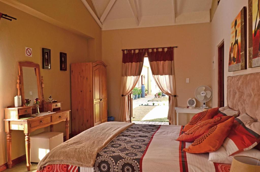 a bedroom with a bed and a desk and a window at Hartley Manor Guest House in Muldersdrift