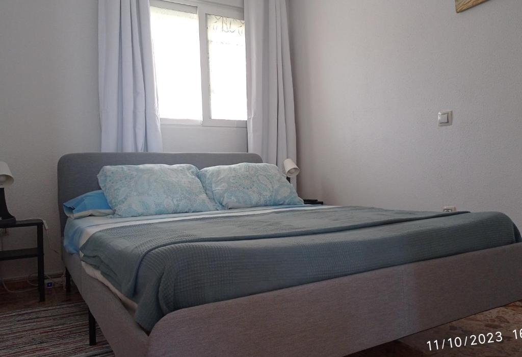 a bedroom with a bed with blue sheets and a window at Casa de huéspedes Villa de las Hortensias in Bustarviejo