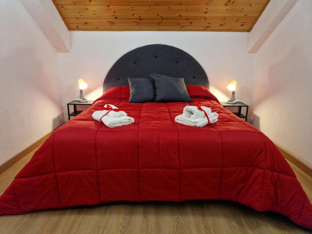 una camera da letto con un letto rosso e asciugamani di [vicino impianti] - Aquila Reale a Sestriere