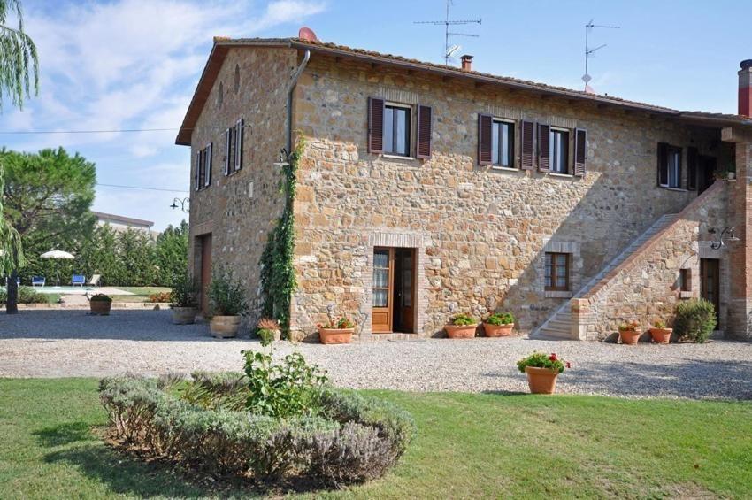 un gran edificio de piedra con un patio delante en Villa Cassia by PosarelliVillas, en Bagno Vignoni