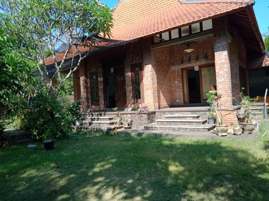 ein Backsteinhaus mit einem Rasenhof davor in der Unterkunft Oemah Bajangan to the Beach in Julah