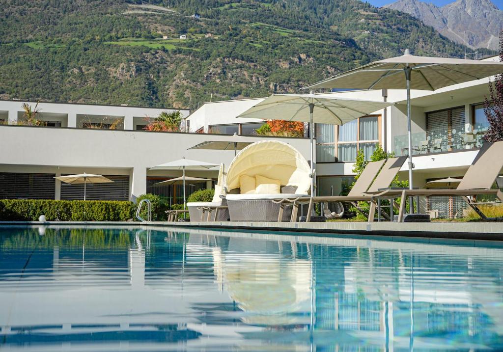 um resort com uma piscina com cadeiras e guarda-sóis em Residence & Sportlodges Claudia em Plaus