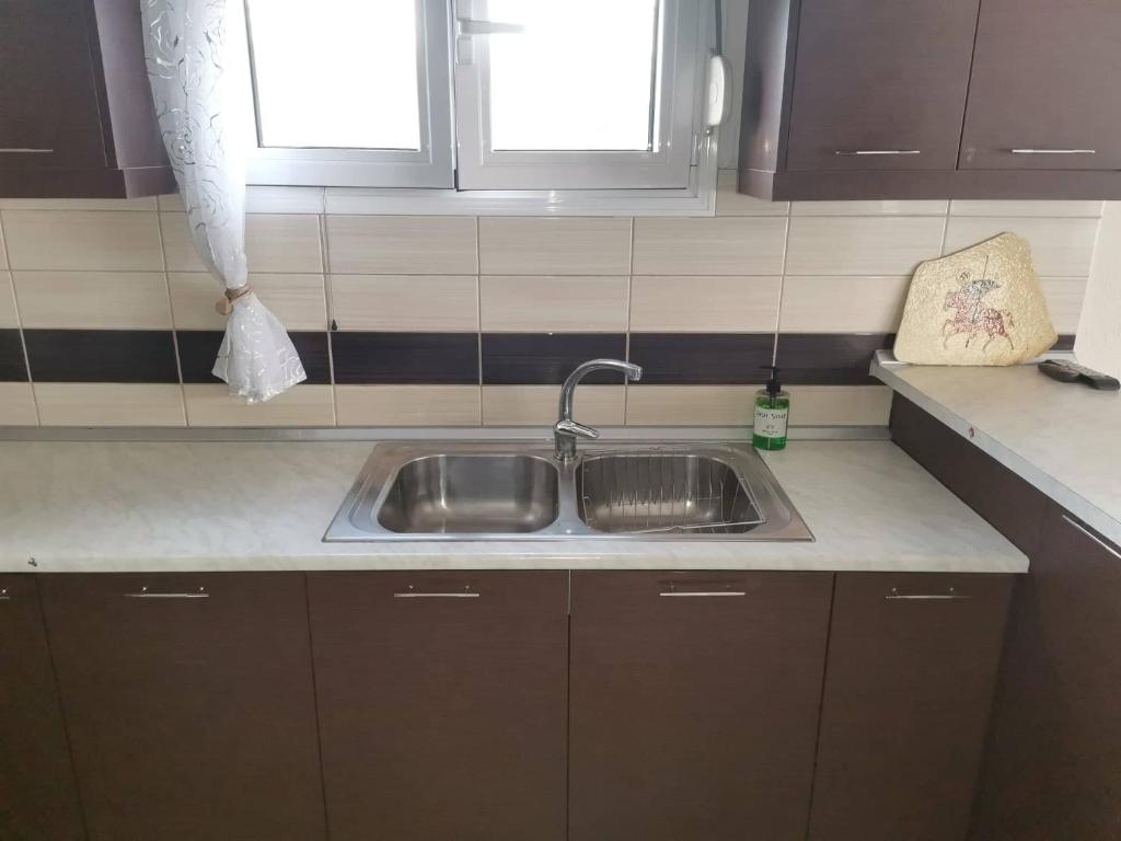 a kitchen counter with a sink and two windows at Cozy Nook Cottage in Faneroméni