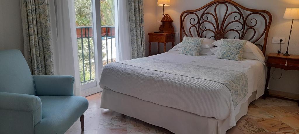 a bedroom with a bed and a chair and a window at miKasa Agua Amarga & SPA in Agua Amarga