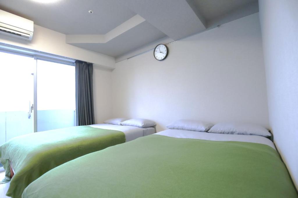 two beds in a room with a clock on the wall at Shinjuku Ryokan Retreat丶Local Tokyo Experience & Short Trips Hub丶walk to Higahsi Shinjuku station YEoL in Tokyo