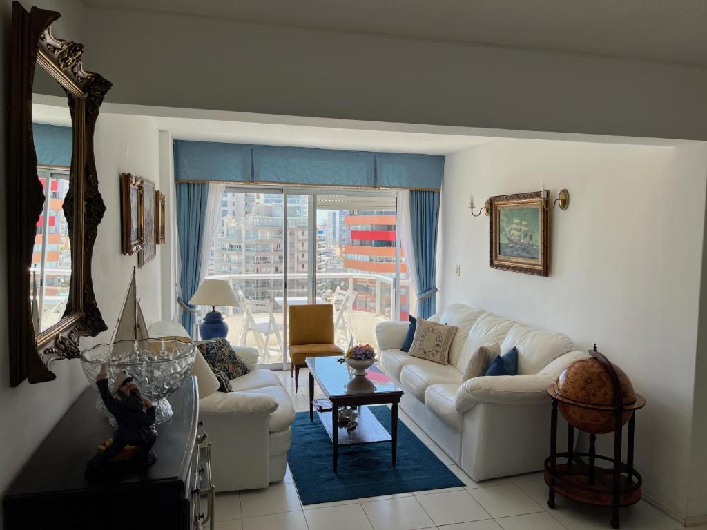 a living room with white furniture and a large window at Torre Marina II Punta del Este in Punta del Este
