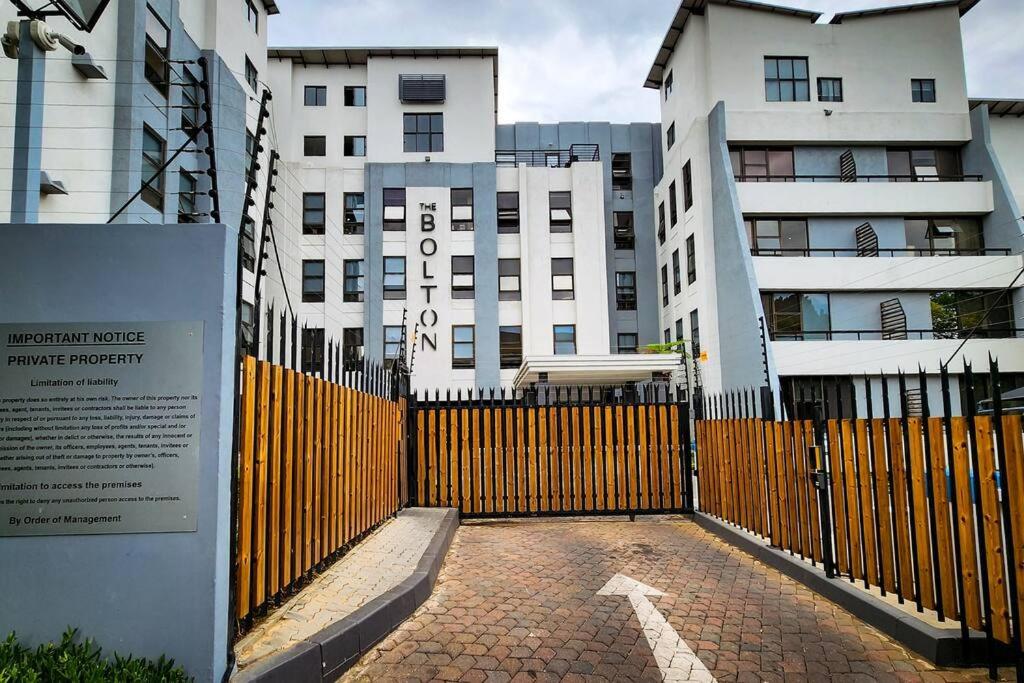 una cerca amarilla delante de algunos edificios altos en No Loadshedding Fast WiFi Lux Apartment en Johannesburgo