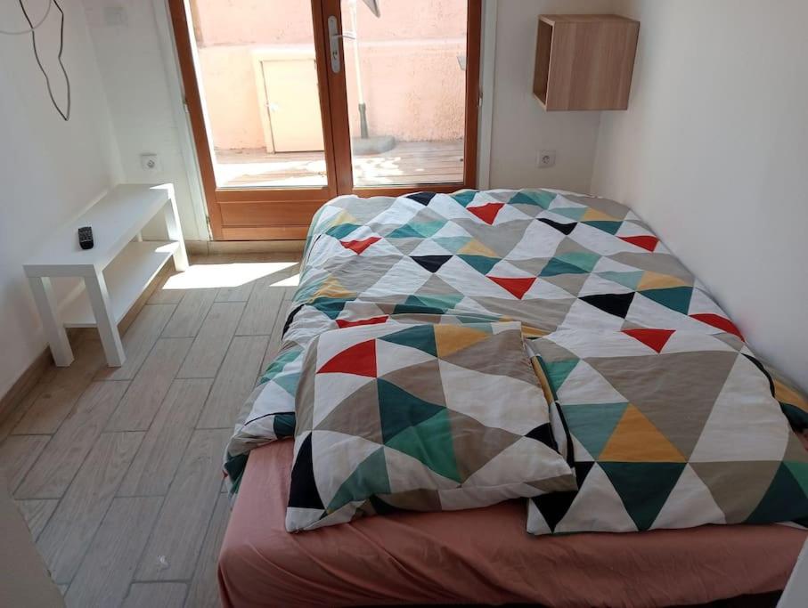 a bed with a quilt on it in a room at studette a la moutonne in La Crau