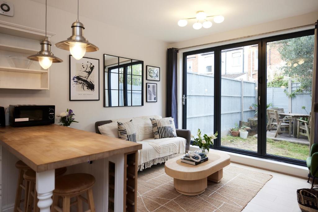 uma sala de estar com um sofá e uma mesa em The Mitcham Hideout - Lovely 2BDR Flat with Garden em Londres