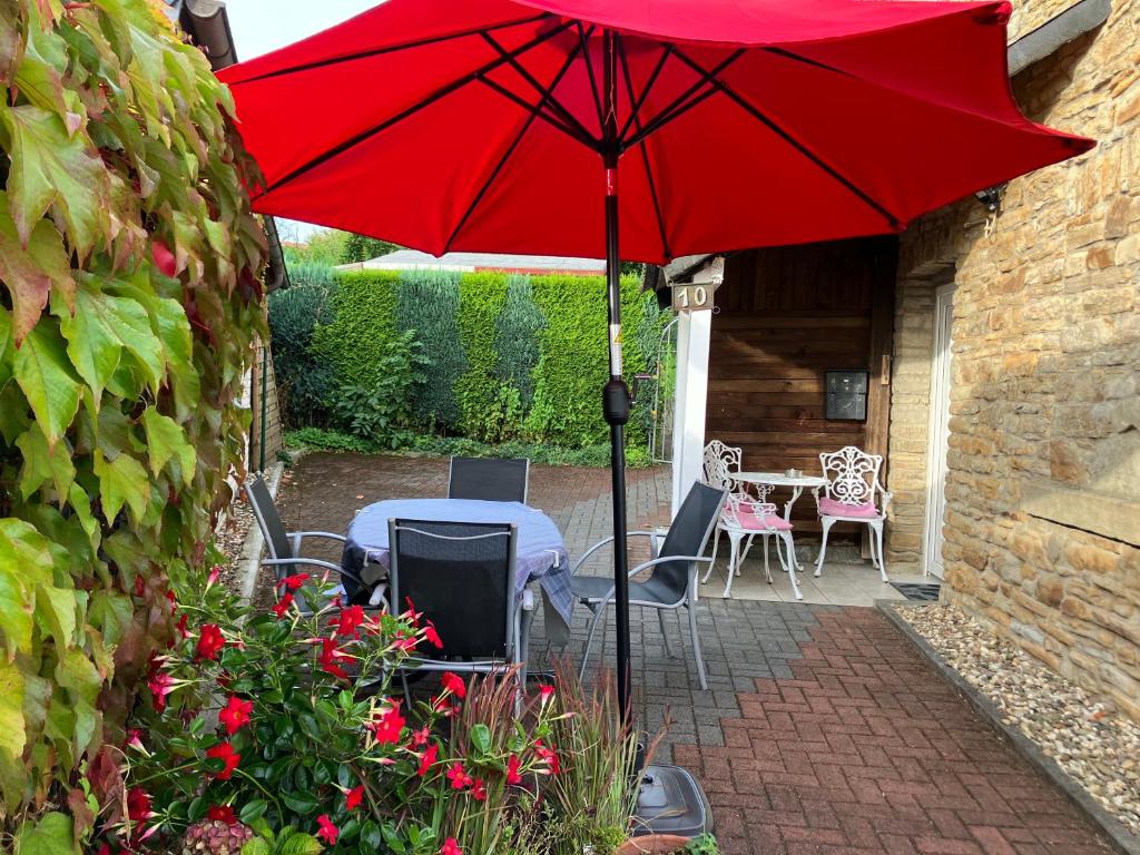 a red umbrella on a patio with a table and chairs at Ferienwohnung im Grünen mit Terrasse WF in Herdecke
