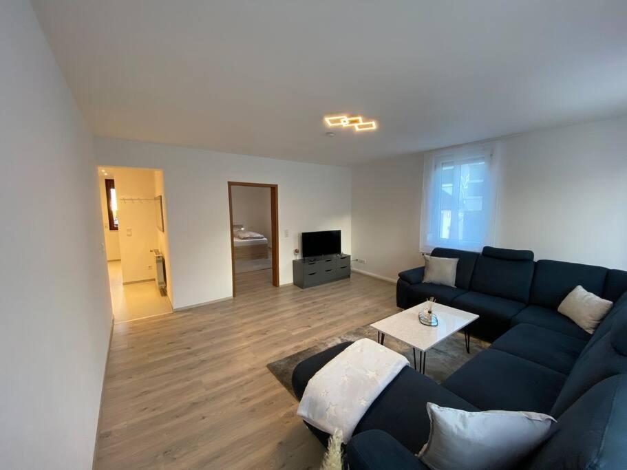 uma sala de estar com um sofá azul e uma mesa em Vali‘s Apartment One em Dettingen an der Erms