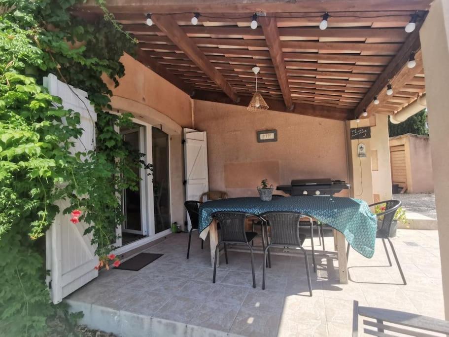 un patio con mesa y sillas bajo una pérgola en Rez de villa pour 4 personnes, en Trets
