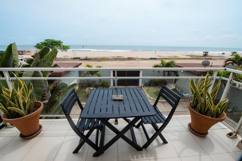 a table and chairs on a balcony with the beach at Duplex moderne avec vue exceptionnelle sur la mer in Pointe-Noire