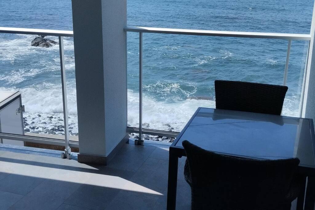 a table and chairs on a balcony with the ocean at 'A Bucha' by The Cliff Coast in Paul do Mar