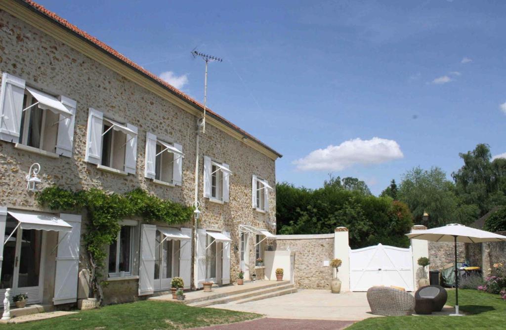 Aincourt的住宿－Maison Hermitage，院子里带雨伞的大型砖砌建筑