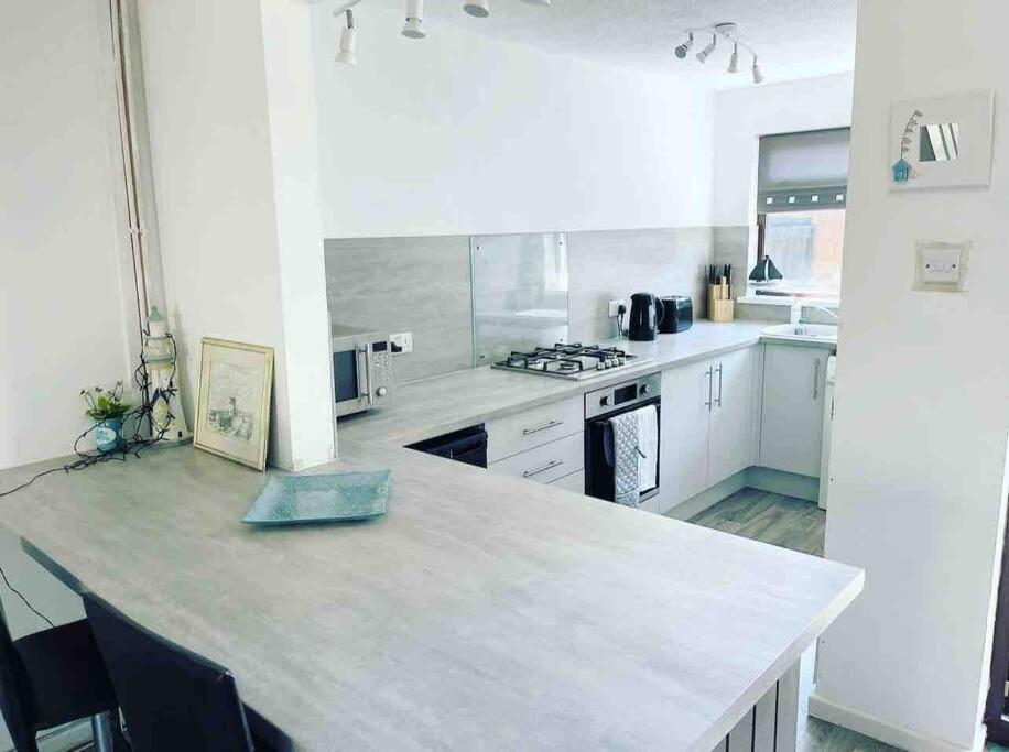 a large white kitchen with a large counter top at Coastal Corner in Porthcawl