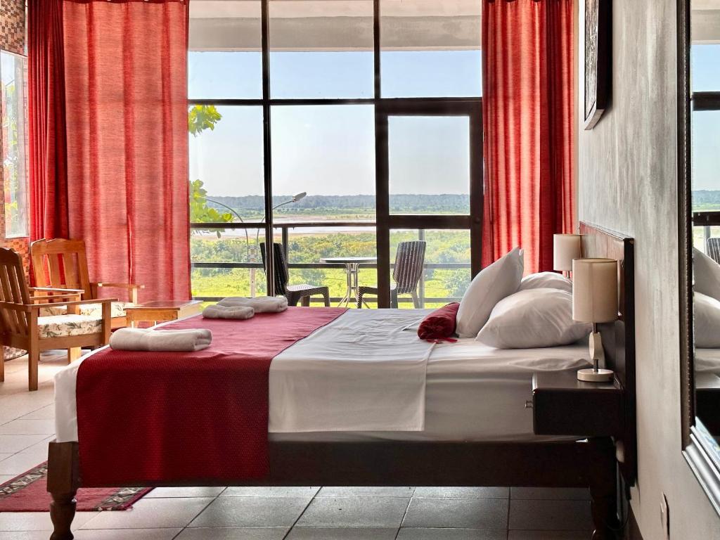 1 dormitorio con 1 cama con cortinas rojas y ventana grande en El Cauchero Hotel Iquitos, en Iquitos