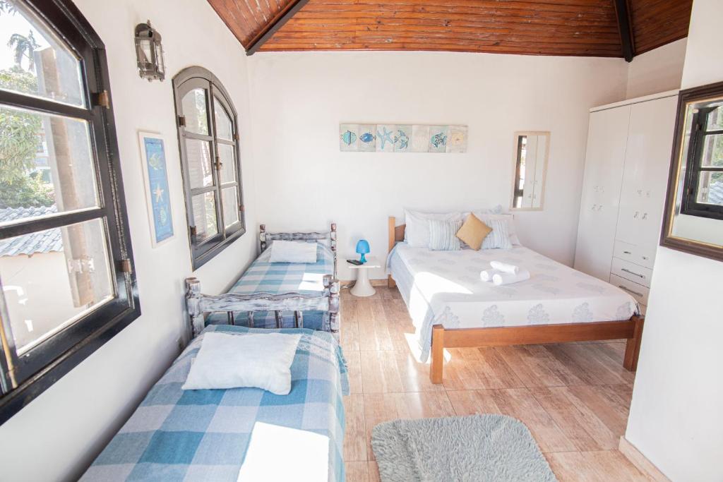 a bedroom with two beds and two windows at Bela Mare Buzios in Búzios