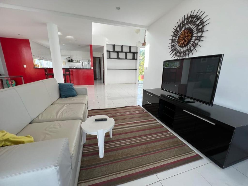 a living room with a couch and a flat screen tv at Casa de praia no Hibiscus Beach Clube, Condomínio Angras de Ipioca. in Maceió